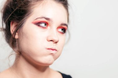 A girl with pouty cheeks, bright red eye makeup. Close-up clipart