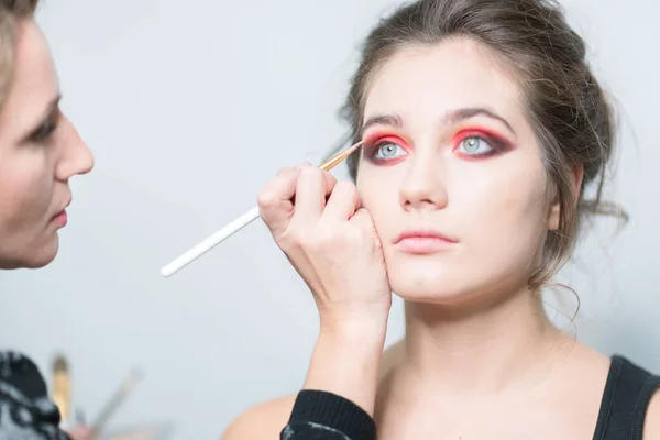 Makeup model. Makeup artist performs make-up in bright colors. Close-up