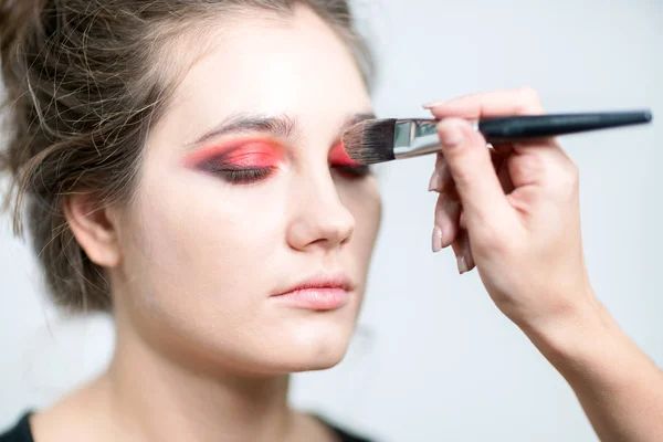 Makeup model closeup. Makeup artist performs make-up in bright colors