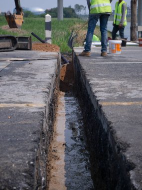 workers are installing concrete drains on the side of the road clipart
