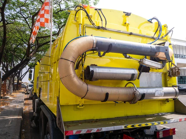 a car for cleaning roads with round brushes on a city street.