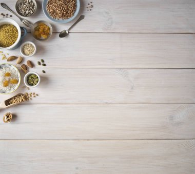 Farklı fındık, tahıl, Kuru üzüm plakaları üzerinde ahşap bir masa. Sedir, kaju fıstığı, fındık, ceviz, badem, kabak çekirdeği, ayçekirdeği, bulgur, buğday, pirinç ve masanın üzerine bir kaşık. Birçok fındık kabuklu ve ahşap beyaz backgro üzerinde chistchenyh