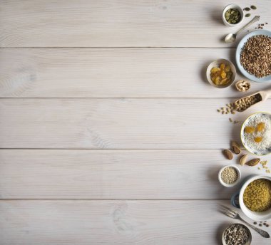 Farklı fındık, tahıl, Kuru üzüm plakaları üzerinde ahşap bir masa. Sedir, kaju fıstığı, fındık, ceviz, badem, kabak çekirdeği, ayçekirdeği, bulgur, buğday, pirinç ve masanın üzerine bir kaşık. Birçok fındık kabuklu ve ahşap beyaz backgro üzerinde chistchenyh