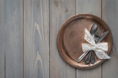 Vintage bıçak, kaşık ve çatal gri bir ahşap zemin üzerinde metal bir plaka üzerinde. Metni için bir yer.