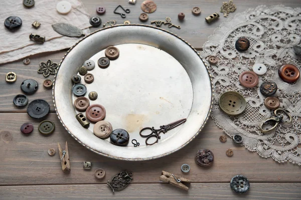 Items for sewing on the background of an old silver plate and an old wooden table