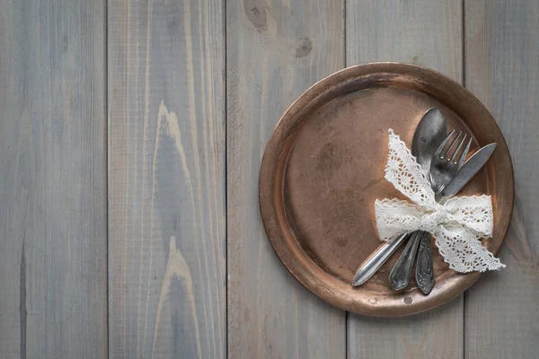 Vintage bıçak, kaşık ve çatal gri bir ahşap zemin üzerinde metal bir plaka üzerinde. Metni için bir yer.