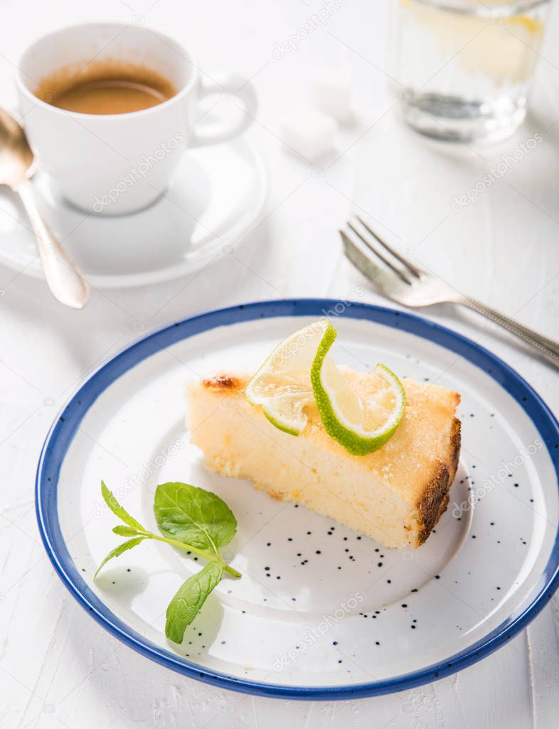 Cheesecake with ricotta cheese on a beautiful plate, vintage fork, a cup of aromatic espresso and water with lemon. Italian food. Sweets. White vintage background.