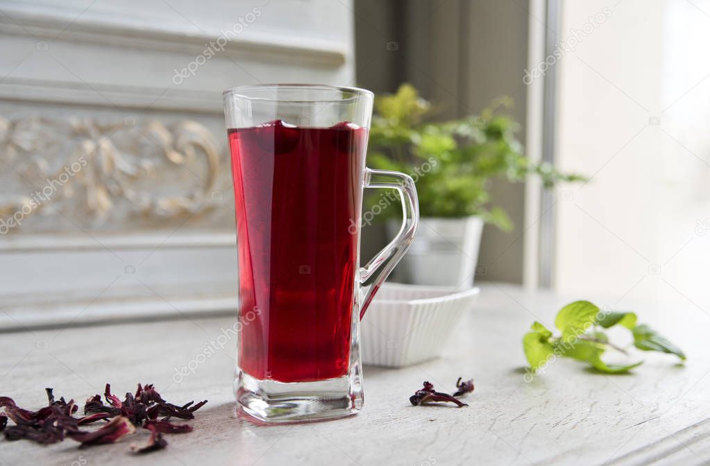 Red hibiscus tea in a transparent glass against the background o