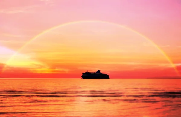 beautiful summer sunset cruise ship going to harbor on sunset on sky beautiful rainbow on ocean water orange sunlight reflection