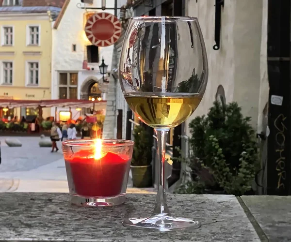 glass of wine  and red candle cup  on table top at restaurant  in Tallinn Estonia