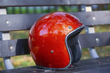 Parkta bankta bir kahverengi ahşap park bankında metalik Kırmızı kask 3/4 3/4 açık yüz kask 