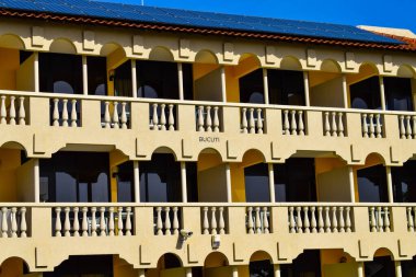 Palmiye ağaçları, beyaz plaj şemsiyeleri ve güneşli bir günde birkaç bulutla Aruba 'nın doğu yakasındaki Eagle Beach' in romantik Bucuti & Tara Resort 'unun nefes kesici manzarası.