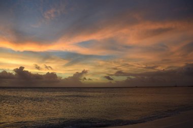Aruba 'nın beyaz plajında turkuaz suyla güzel altın gün batımı.