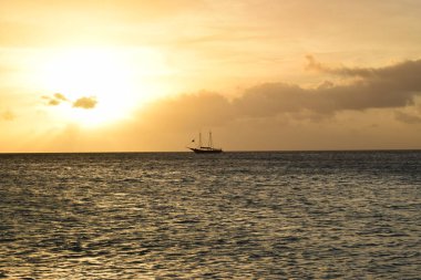 Aruba 'nın beyaz plajında turkuaz suyla güzel altın gün batımı.