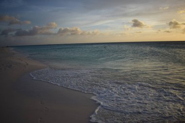 Aruba 'nın beyaz plajında turkuaz suyla güzel altın gün batımı.