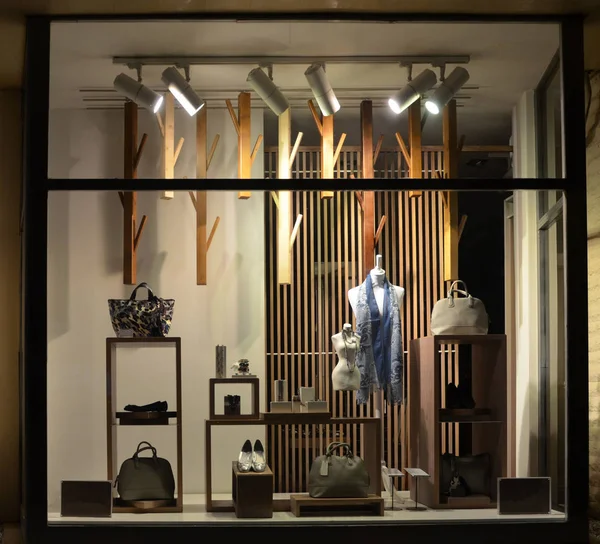 Evening boutique window with shoes, bags and mannequin.