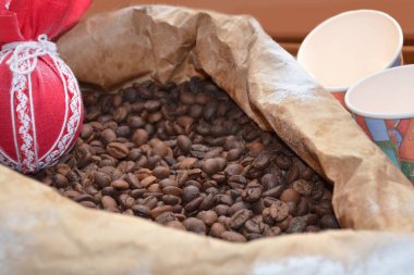 Kahve çekirdekleri torba, kağıt bardak ve kırmızı dekorasyon arka plan.