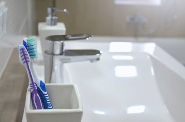 Beyaz cam, sabun ile dağıtıcı, lavabo banyo arka plan bulanık İç mekândaki ile diş fırçaları.