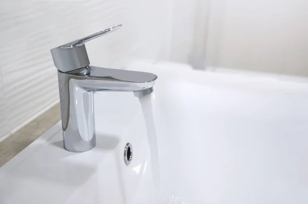 İçinden su akışı akar, bir krom musluk ile beyaz lavabo lavabo. Görüntü