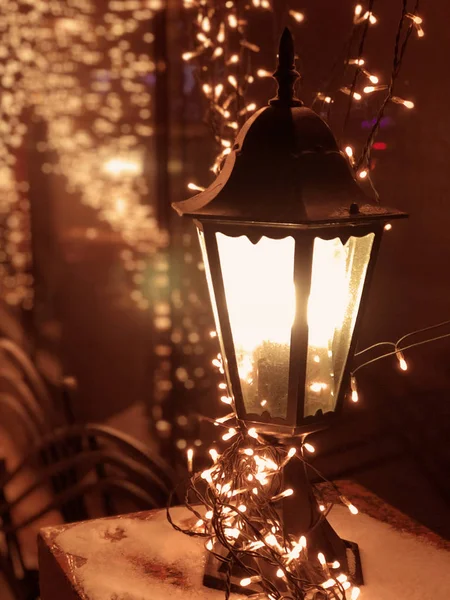 A lantern with a bright garland, glowing at night and sparkling golden bokeh lights on a dark background. Image