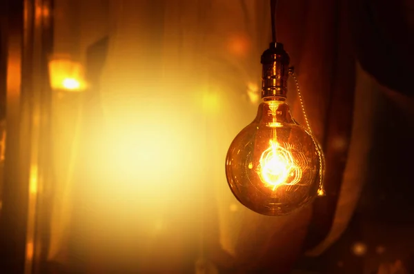 The light bulb glows warm light on the yellow-brown background. Empty place for text. Image