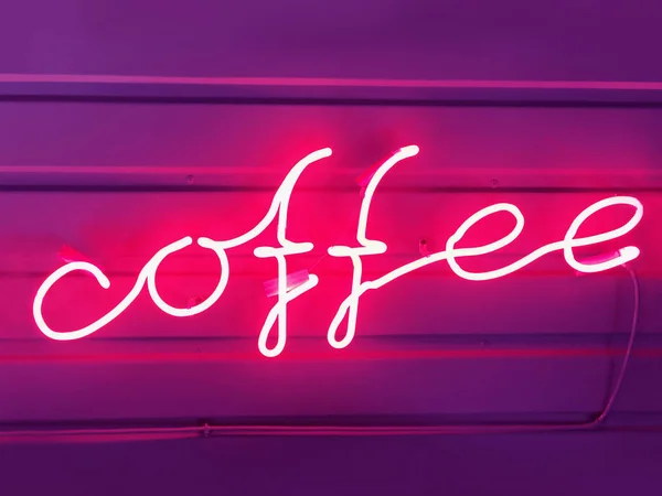 Words of coffee from a pink neon tube.