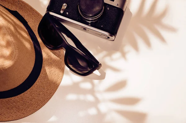 Gafas de sol, sombrero, cámara sobre un fondo claro bajo la sombra o —  Fotos de Stock