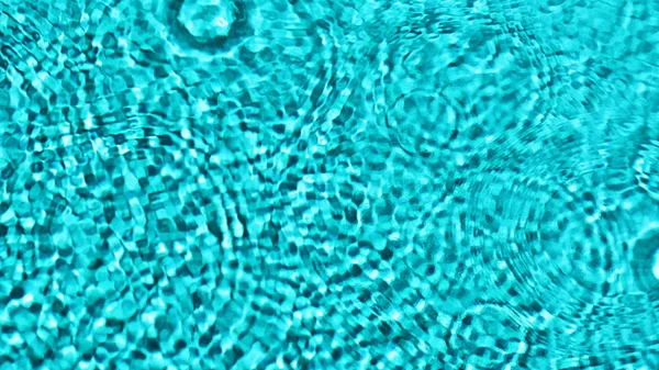 Ripples of water drops, circles on turquoise blue water, reflection, structure, texture, pool, abstract background, blurred.with space for tex