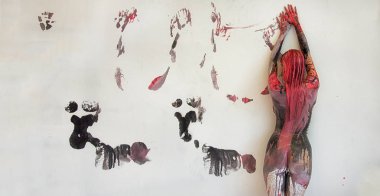 Young artistically abstract painted woman with black red white, paint, rolls off in front of white wall in studio and leaves colorful color prints. clipart
