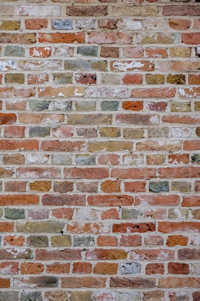 Brick wall, with colorful colored bricks, red, green, gray, brown in summer in Bruges, Belgium, red wall texture, as background.