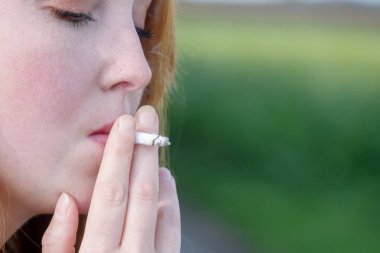 Güzel bir portre genç seksi kırmızı saçlı, kırmızı saçlı kadın düşünceli bir kendi kendine haddelenmiş sigara açık havada, metin için alan, kopya alanı