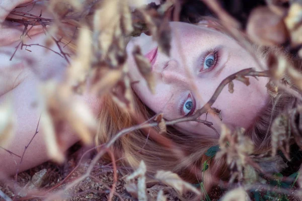 Hermosa chica sexy de pelo rojo joven encantadora acostada debajo de una rama con hojas de otoño de oro, en el parque, con sonrisa en la cara . — Foto de Stock