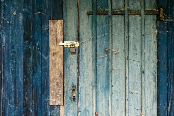 Azul turquesa vieja pared de madera de un cobertizo con cerradura y puerta cerrada con cerradura con grano de madera rústica, candado y muchas telarañas pequeñas —  Fotos de Stock