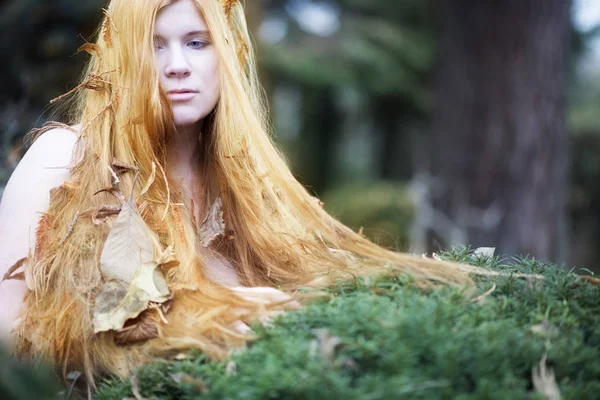 Portrait of a young beautiful lovely sexy woman with free shoulders leaning on yew, the long red hair full of autumn leaves. — Stock Photo, Image