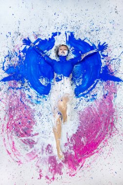 Young nude artist woman in blue, pink white, paint, painted, lies on the ground like an angel and raises her arms. Abstract body art, abstract expressionism painting, clipart