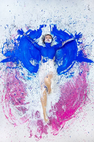 Jovem artista nua mulher em azul, rosa branco, pintar, pintado, encontra-se no chão como um anjo e levanta os braços. Arte corporal abstrata, pintura expressionista abstrata , — Fotografia de Stock