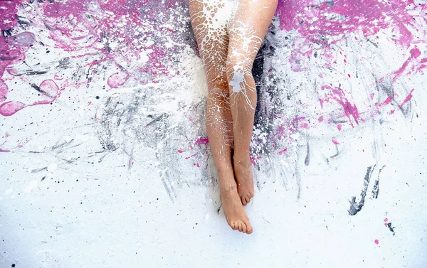 Beautiful woman legs with white paint splashed on painted studio floor — Stock Photo, Image