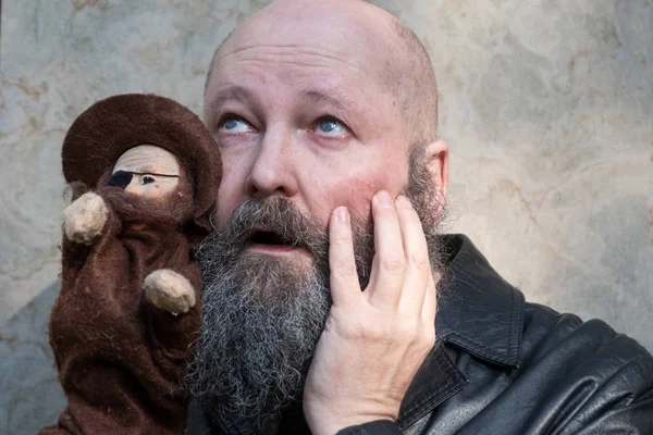 idiosyncratic crazy artist Father with beard, with astonished expression, plays with a hand puppet