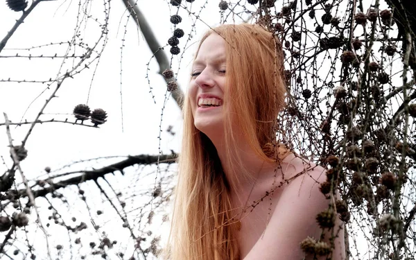 Belle jeune fille sexy avec de beaux cheveux rouges magnifiques riant bruyamment dans un arbre w — Photo