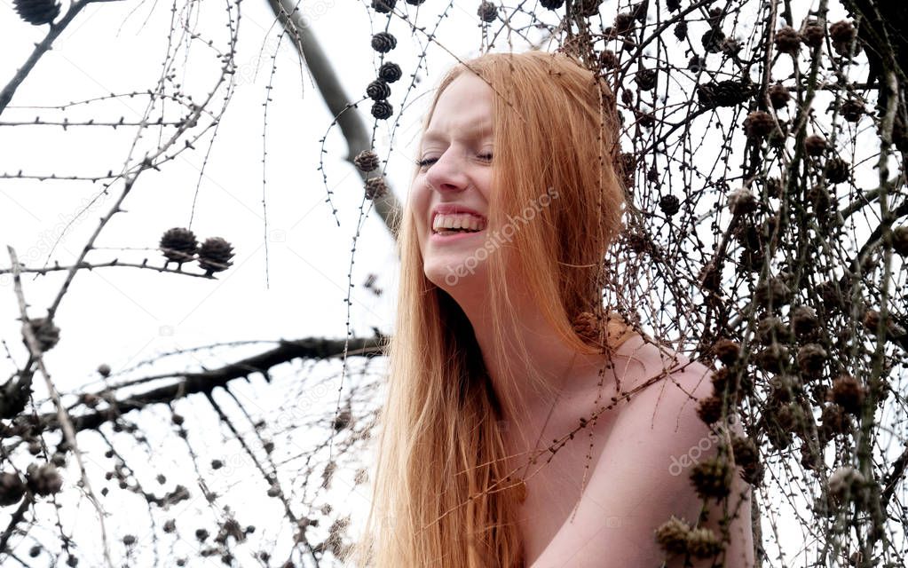 beautiful young sexy girl with beautiful gorgeous red hair laughing loudly in a tree w