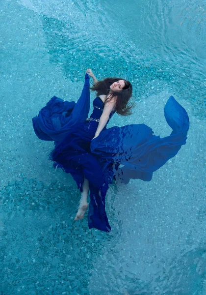 Όμορφη νεαρή γυναίκα σε μπλε βράδυ φόρεμα επιπλέουν χωρίς βάρος κομψό στο νερό — Φωτογραφία Αρχείου