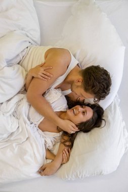 Beyaz yatak yatakta yatan ve sarılma güzel genç çift üst görünümü, kopya alanı