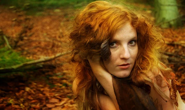 Retrato de una hermosa joven de pelo rojo, con hojas doradas de otoño, en el bosque, con una sonrisa amistosa en la cara, espacio para copiar — Foto de Stock