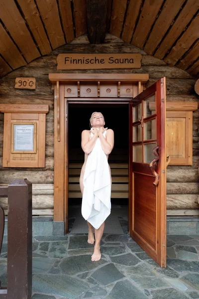 Mulher bonita com toalha deixar finlandês sauna de madeira — Fotografia de Stock
