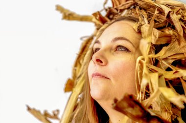 Portrait of a young sexy chubby fat curvy woman with brown hair artfully covered between dry, withered decorative banana tree, looking like Cleopatra, white Background, Copy space
