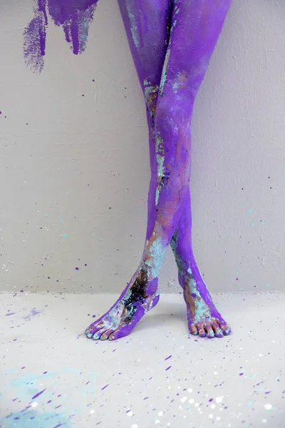 beautiful sexy legs and feet on tiptoe of a young artistically abstract painted woman, ballerina with white, blue and purple paint. Creative body art painting, copy space