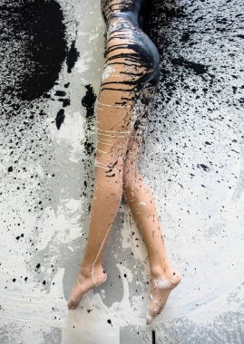 Güzel bacakları ve ayakları, sanatsal açıdan soyut, iç çamaşırlı, spor kıyafetli, siyah beyaz boyalı, stüdyonun renkli boyanmış zemininde yatan,.