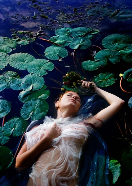 Genç, mutsuz, kıvırcık, kızıl saçlı Ophelia. Gözleri kapalı, beyaz elbiseli çiçekli. Suda, nilüferlerin arasında ölüyor.