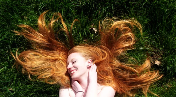 一个年轻性感的红头发女人的美丽画像 在夏日的阳光下快乐地躺着 悠闲地躺在绿茵的草地上 红头发飘扬在头顶上 复制空间 — 图库照片