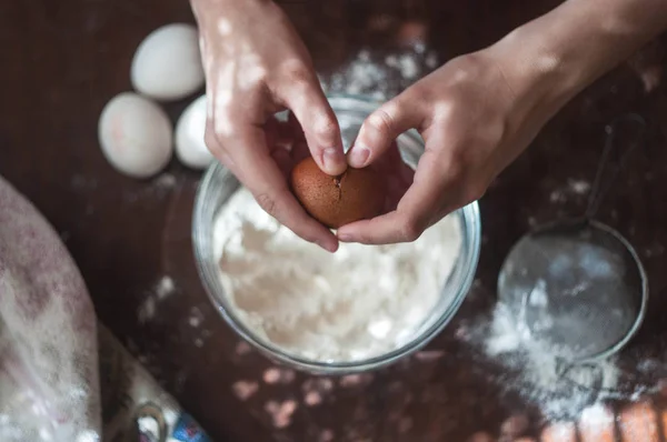 Yumurta çatlama ve un içine ekleme. Bir tavuk yumurta, halı ve bir elek un için. Pişirme işlemi. Ahşap masa